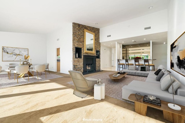 carpeted living room with a fireplace and a towering ceiling