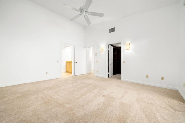 unfurnished bedroom featuring connected bathroom, ceiling fan, high vaulted ceiling, and light carpet