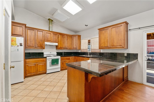 kitchen with white appliances, light tile patterned floors, vaulted ceiling, and kitchen peninsula