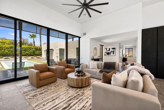 living room featuring ceiling fan, a high ceiling, and plenty of natural light