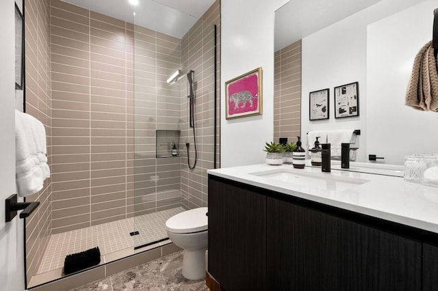 bathroom featuring vanity, tiled shower, and toilet