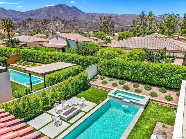 view of pool featuring a patio area, a mountain view, and an in ground hot tub