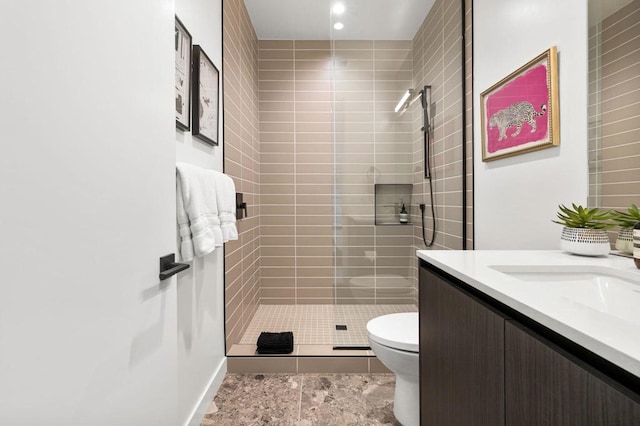 bathroom featuring vanity, toilet, and a tile shower