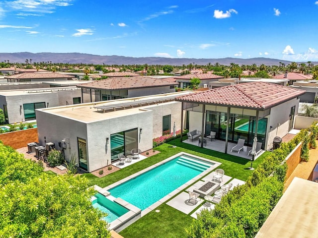 back of property featuring a patio area, a mountain view, outdoor lounge area, and a lawn