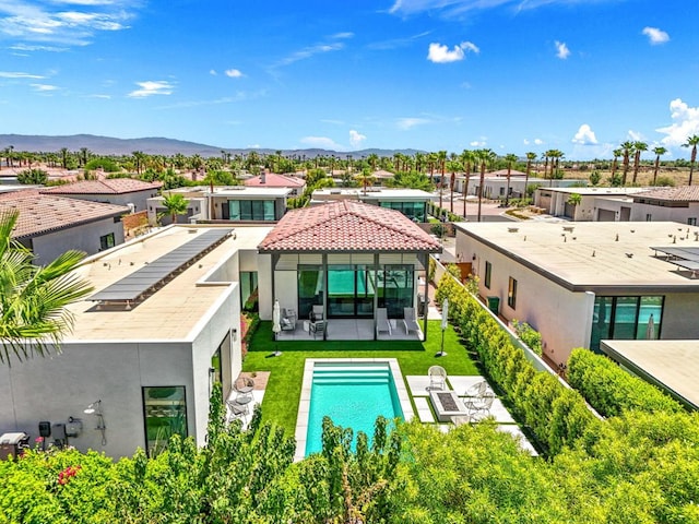 back of house with a yard, a patio area, a fenced in pool, and a mountain view