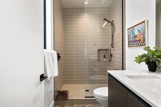 bathroom featuring vanity, toilet, tile patterned floors, and tiled shower