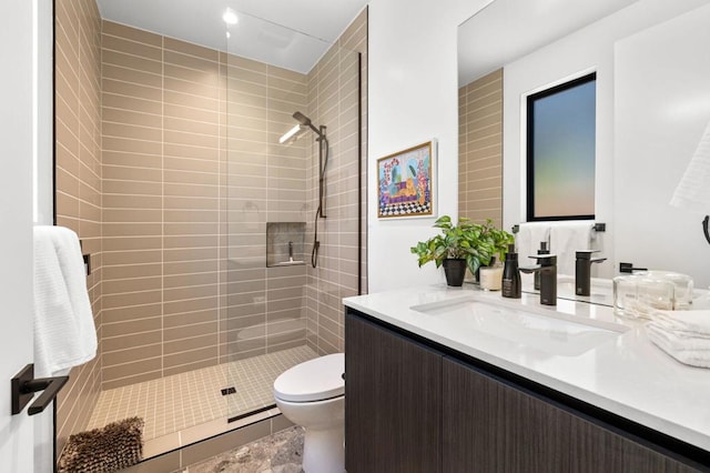 bathroom with vanity, toilet, and a tile shower