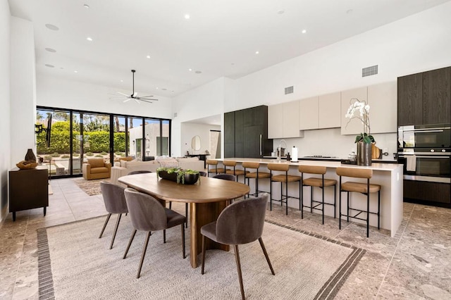 dining room featuring ceiling fan, a towering ceiling, and sink