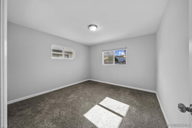 unfurnished room featuring dark carpet