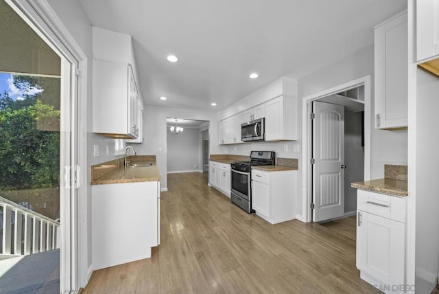 kitchen featuring sink, light stone counters, light hardwood / wood-style floors, white cabinets, and appliances with stainless steel finishes