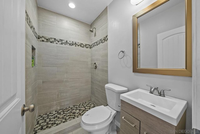 bathroom featuring hardwood / wood-style floors, vanity, toilet, and tiled shower