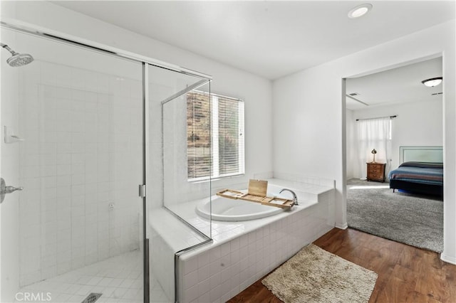 bathroom featuring plus walk in shower and hardwood / wood-style floors