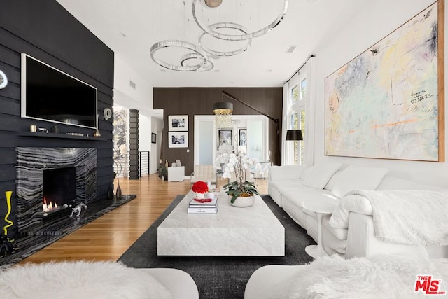 living room with wood-type flooring, a fireplace, and wooden walls