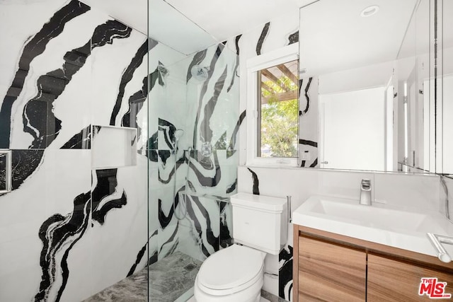 bathroom with a tile shower, vanity, and toilet