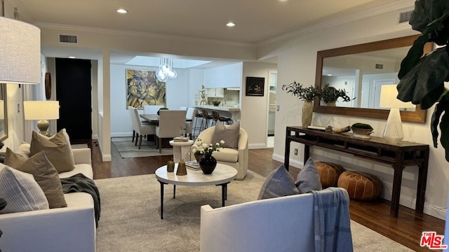 living room featuring hardwood / wood-style flooring, an inviting chandelier, and crown molding