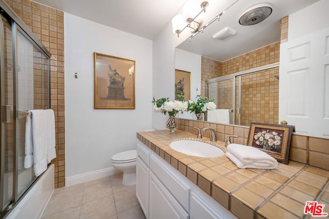 full bathroom featuring tile patterned floors, shower / bath combination with glass door, vanity, and toilet