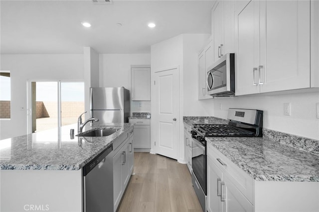 kitchen with white cabinetry, a kitchen island with sink, light hardwood / wood-style flooring, sink, and stainless steel appliances