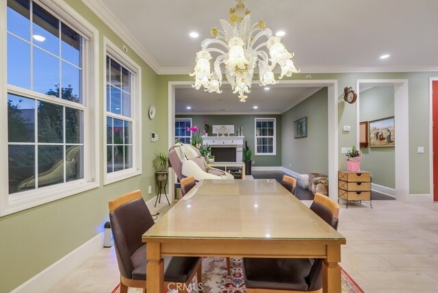 tiled dining space with a chandelier, a fireplace, and crown molding