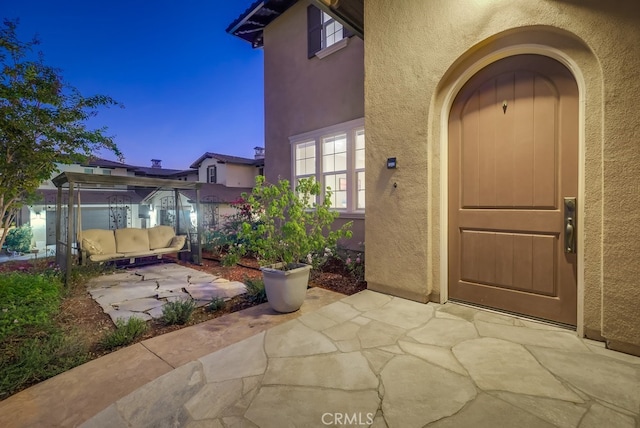 exterior entry at dusk with a patio area