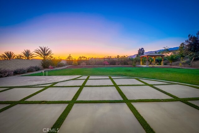 patio terrace at dusk with a gazebo and a yard