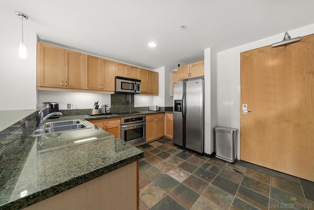 kitchen with appliances with stainless steel finishes, decorative backsplash, dark stone counters, hanging light fixtures, and sink