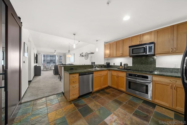 kitchen with kitchen peninsula, dark colored carpet, appliances with stainless steel finishes, pendant lighting, and sink