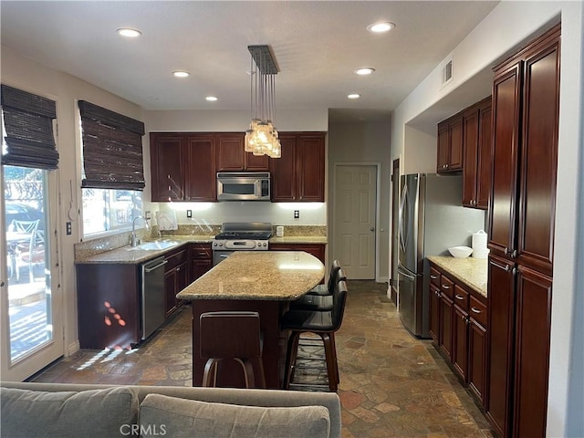 kitchen featuring appliances with stainless steel finishes, sink, pendant lighting, a center island, and a breakfast bar area