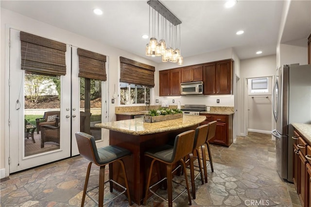 kitchen with plenty of natural light, a center island, hanging light fixtures, and appliances with stainless steel finishes