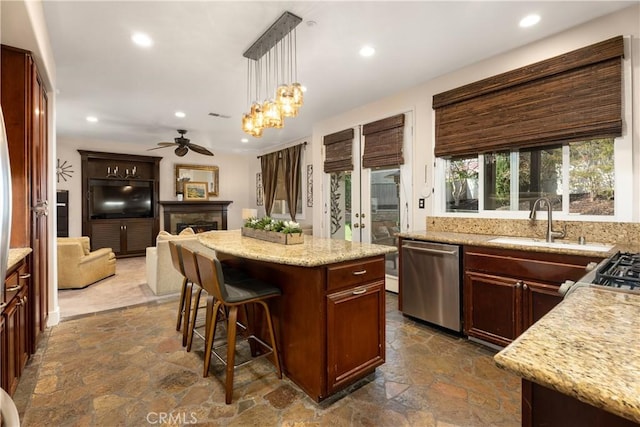 kitchen with sink, hanging light fixtures, stainless steel appliances, a kitchen island, and ceiling fan with notable chandelier