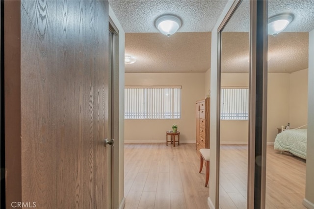 corridor with light hardwood / wood-style floors and a textured ceiling