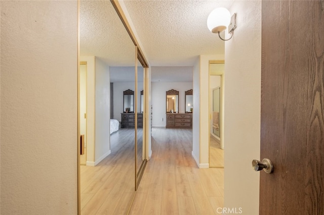 corridor featuring a textured ceiling and light wood-type flooring