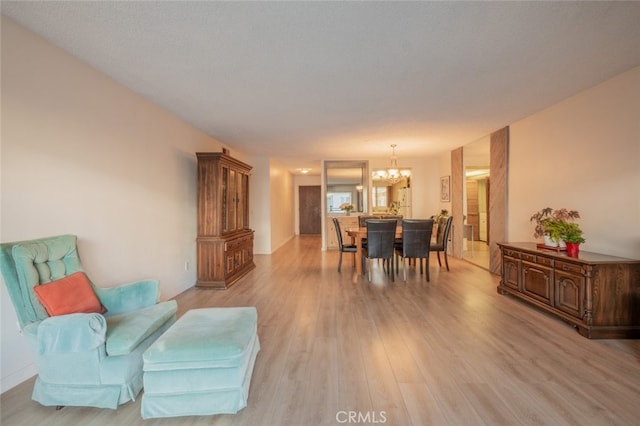 dining room featuring light wood-type flooring, a textured ceiling, and an inviting chandelier