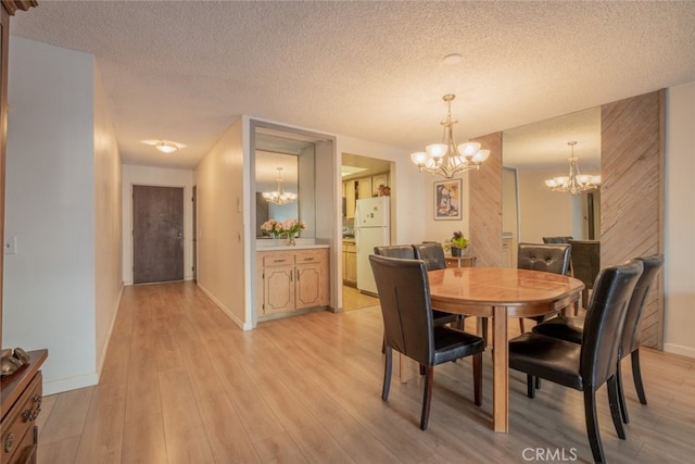 dining area featuring an inviting chandelier, a textured ceiling, and light hardwood / wood-style flooring