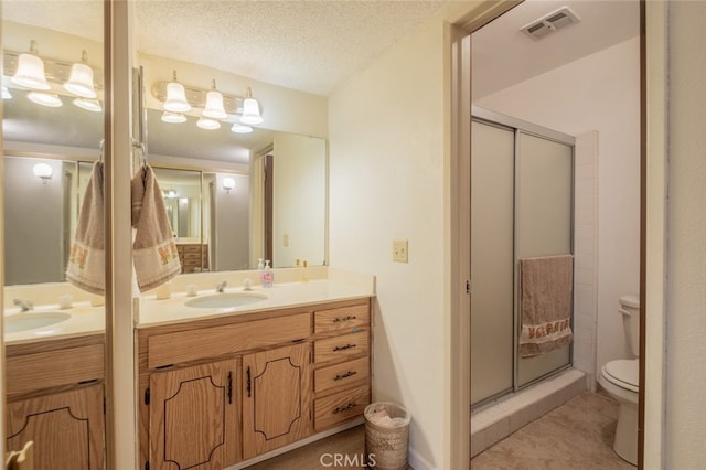 bathroom with vanity, toilet, a textured ceiling, and walk in shower