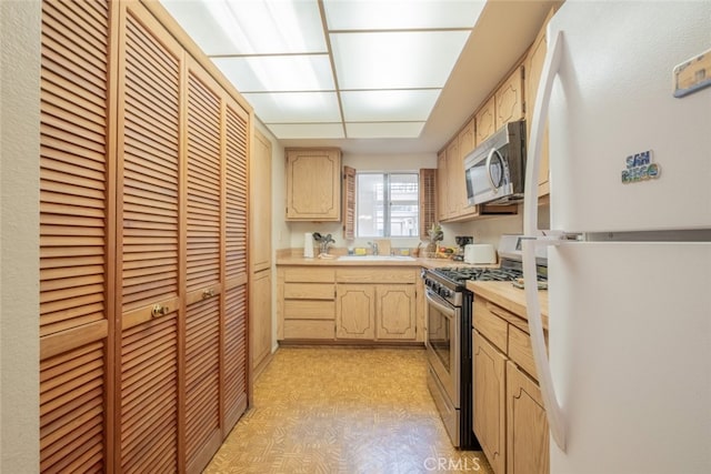 kitchen with light brown cabinets, sink, and appliances with stainless steel finishes