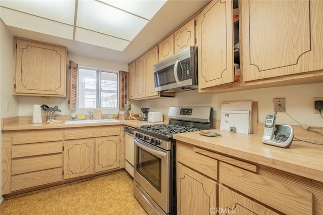 kitchen featuring light brown cabinetry, sink, and appliances with stainless steel finishes