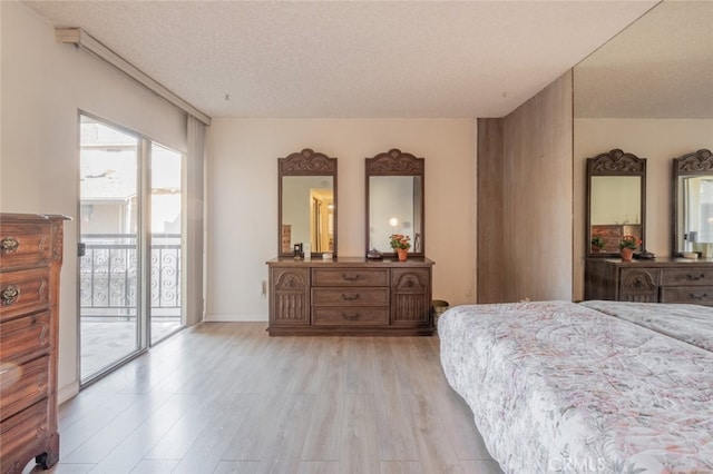 bedroom with access to exterior, a textured ceiling, and light hardwood / wood-style flooring