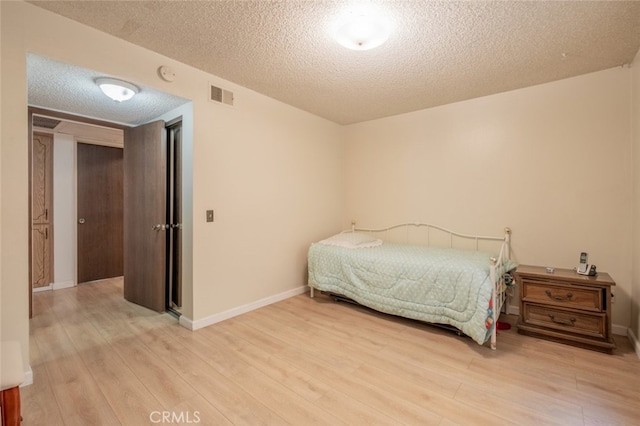 bedroom with a textured ceiling and light hardwood / wood-style flooring