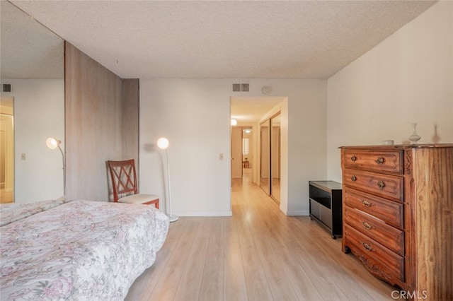 bedroom with a textured ceiling and light hardwood / wood-style floors