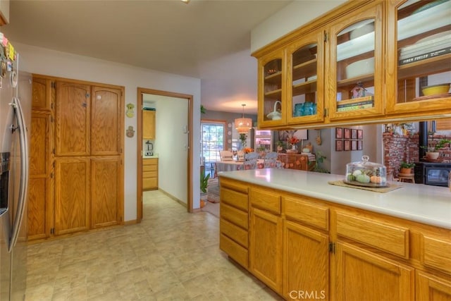 kitchen featuring brown cabinets, glass insert cabinets, black microwave, light countertops, and stainless steel fridge with ice dispenser