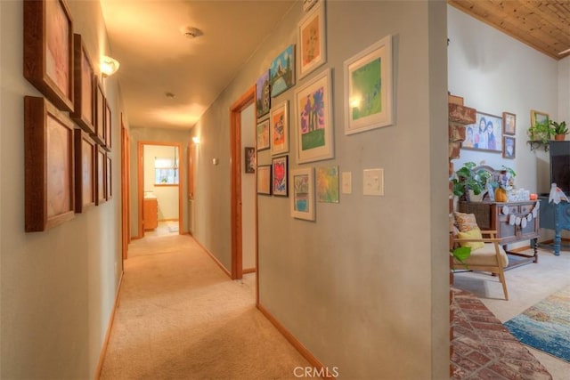 corridor featuring baseboards and light carpet