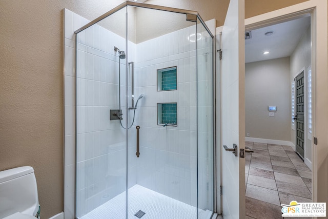 bathroom with a shower with door and toilet