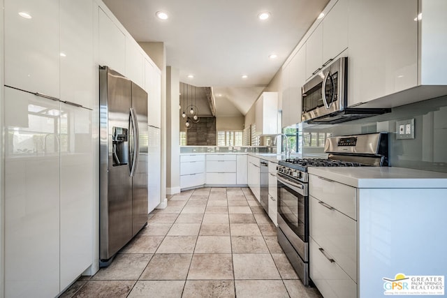 kitchen featuring white cabinets, stainless steel appliances, light tile patterned floors, and vaulted ceiling