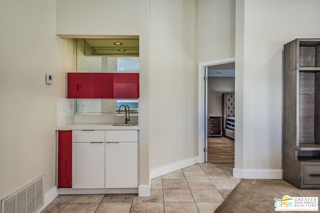 kitchen with light tile patterned flooring, white cabinetry, and sink