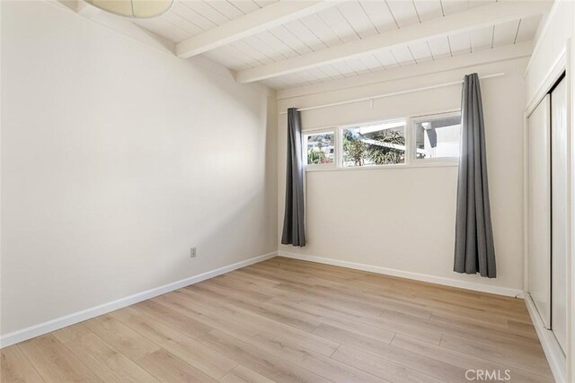 empty room with beamed ceiling, wood ceiling, and light hardwood / wood-style floors