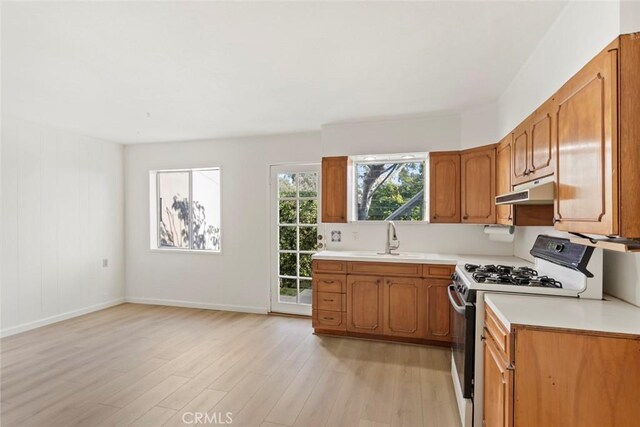 kitchen with sink, light hardwood / wood-style flooring, and gas range gas stove