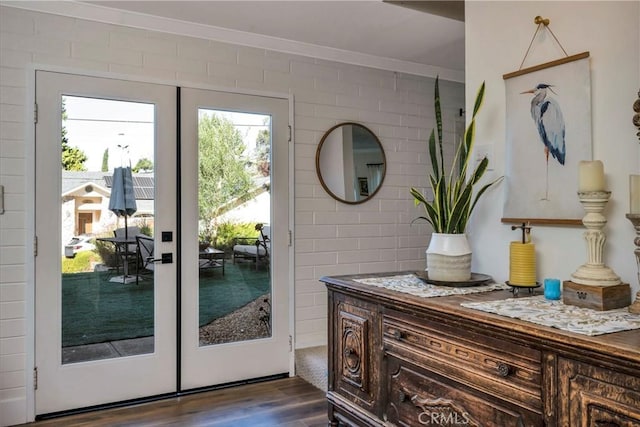 entryway featuring french doors, dark wood-type flooring, and brick wall