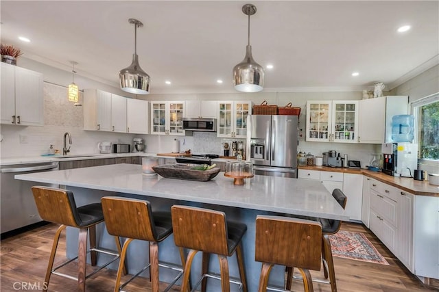 kitchen with appliances with stainless steel finishes, sink, a spacious island, and white cabinetry