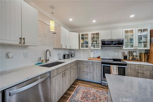 kitchen with stainless steel appliances, light stone counters, pendant lighting, dark hardwood / wood-style flooring, and sink