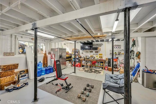 basement with a workshop area and stainless steel refrigerator with ice dispenser